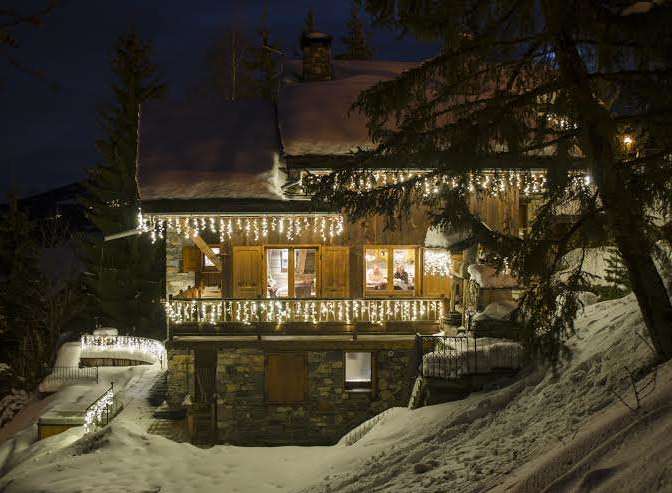 Spectacular chalet nestled in the snowy mountains, adorned with enchanting Christmas lights.