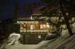 Spectacular chalet nestled in the snowy mountains, adorned with enchanting Christmas lights.