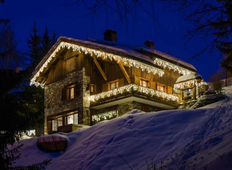 This stunning chalet boasts a beautiful stone and wood exterior, adorned with charming Christmas lights.