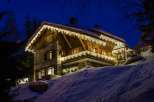 This stunning chalet boasts a beautiful stone and wood exterior, adorned with charming Christmas lights.