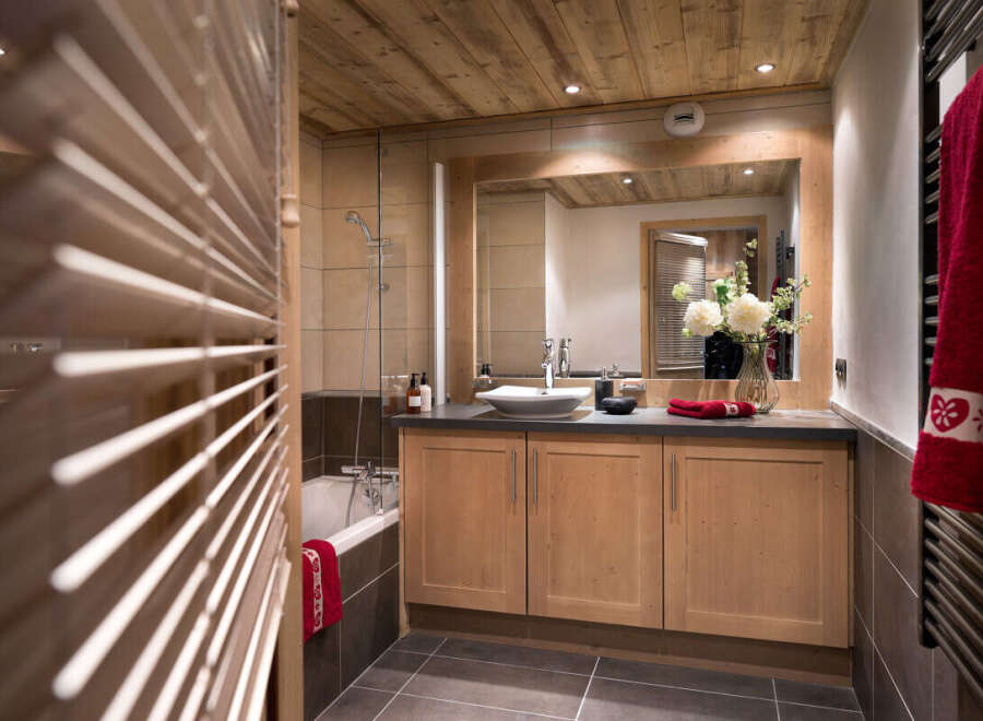 This stunning bathroom boasts a spacious design with light wood cabinets and a walk-in shower.