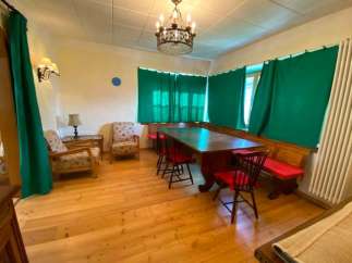 This charming property features a cozy dining area with a large wooden table and comfortable seating.