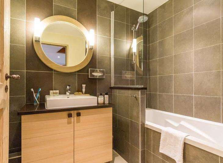 Step into a beautifully designed bathroom featuring a modern vanity and a sleek, round mirror.