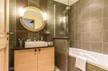Step into a beautifully designed bathroom featuring a modern vanity and a sleek, round mirror.