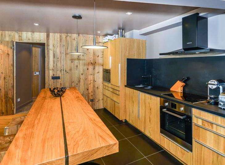 This stunning kitchen boasts a modern design with a rustic touch, featuring wooden cabinetry and a sleek black countertop.