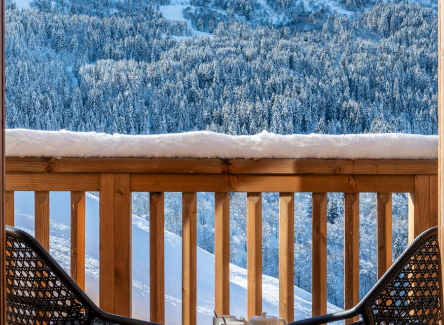 Enjoy breathtaking mountain views from this stunning balcony, complete with comfortable outdoor seating and a small table perfect for morning coffee.