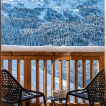 Enjoy breathtaking mountain views from this stunning balcony, complete with comfortable outdoor seating and a small table perfect for morning coffee.