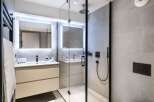 This modern bathroom boasts a spacious walk-in shower with a rainfall shower head, sleek black fixtures, and elegant gray tile.