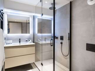 This modern bathroom boasts a spacious walk-in shower with a rainfall shower head, sleek black fixtures, and elegant gray tile.