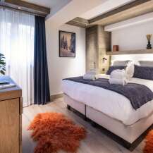 This luxurious bedroom boasts a king-size bed with plush bedding, complemented by a stylish wooden headboard and built-in storage.