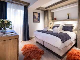 This luxurious bedroom boasts a king-size bed with plush bedding, complemented by a stylish wooden headboard and built-in storage.