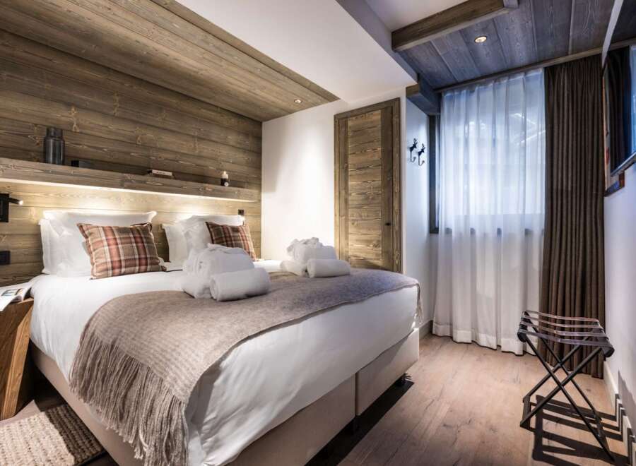 This luxurious bedroom boasts a stunning wood-paneled ceiling and walls, creating a cozy and inviting atmosphere.