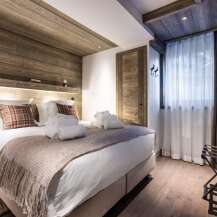 This luxurious bedroom boasts a stunning wood-paneled ceiling and walls, creating a cozy and inviting atmosphere.