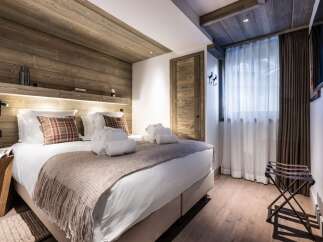This luxurious bedroom boasts a stunning wood-paneled ceiling and walls, creating a cozy and inviting atmosphere.