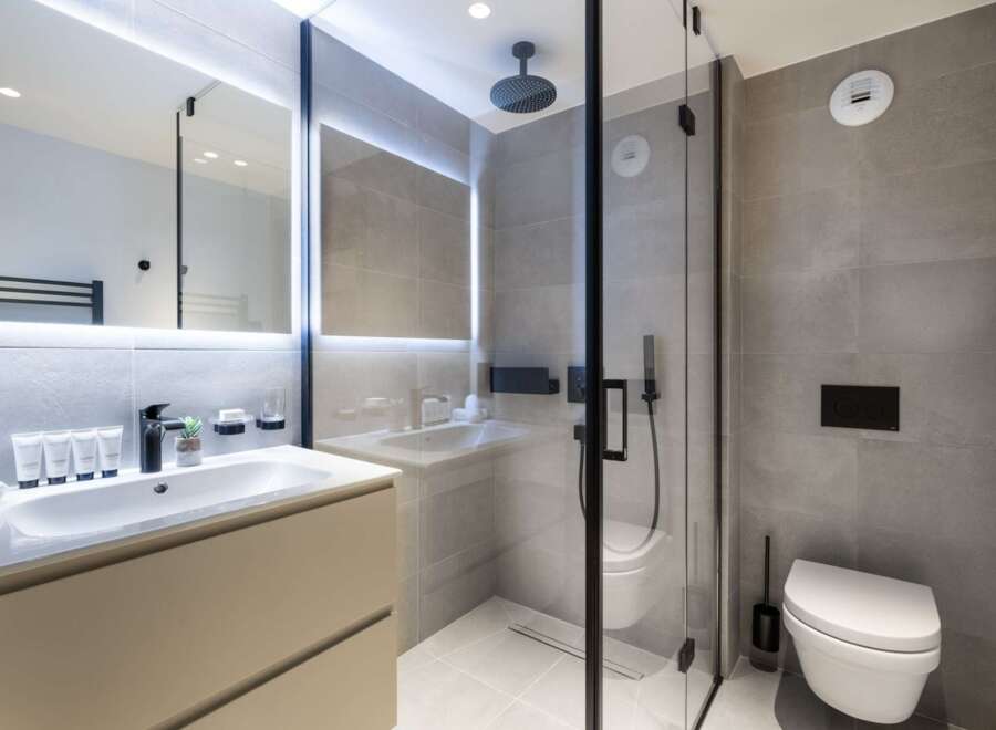 Modern bathroom with a walk-in shower, sleek sink vanity, and wall-mounted toilet.