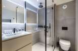 Modern bathroom with a walk-in shower, sleek sink vanity, and wall-mounted toilet.