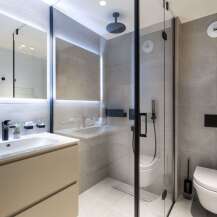 Modern bathroom with a walk-in shower, sleek sink vanity, and wall-mounted toilet.