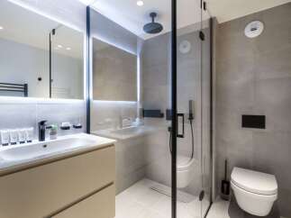Modern bathroom with a walk-in shower, sleek sink vanity, and wall-mounted toilet.