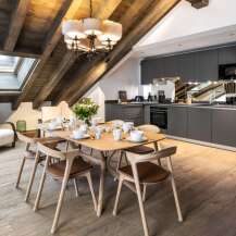 This stunning chalet boasts a spacious open-plan living area with a rustic wooden beamed ceiling and large skylights, creating a bright and airy atmosphere.