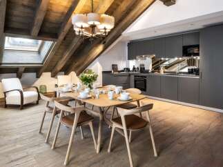 This stunning chalet boasts a spacious open-plan living area with a rustic wooden beamed ceiling and large skylights, creating a bright and airy atmosphere.
