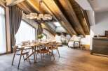 This stunning chalet boasts a spacious open-plan living area with exposed wooden beams and a large dining table perfect for family gatherings.