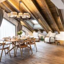 This stunning chalet boasts a spacious open-plan living area with exposed wooden beams and a large dining table perfect for family gatherings.