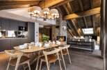 This stunning chalet boasts a spacious open-plan living area with a rustic wooden beamed ceiling and a cozy fireplace, perfect for relaxing after a day on the slopes.