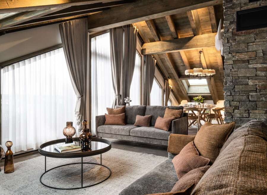 This stunning chalet boasts a spacious open-plan living area with floor-to-ceiling windows offering breathtaking views, a cozy fireplace, and luxurious furnishings.