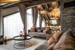 This stunning chalet boasts a spacious open-plan living area with floor-to-ceiling windows offering breathtaking views, a cozy fireplace, and luxurious furnishings.
