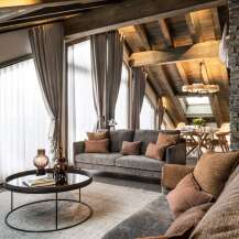 This stunning chalet boasts a spacious open-plan living area with floor-to-ceiling windows offering breathtaking views, a cozy fireplace, and luxurious furnishings.