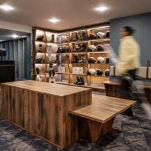 This stunning ski rental shop boasts a modern design with rustic wooden furniture and sleek shelving units showcasing an array of skis, boots, and helmets.