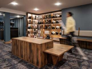 This stunning ski rental shop boasts a modern design with rustic wooden furniture and sleek shelving units showcasing an array of skis, boots, and helmets.
