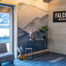 This stunning Méribel chalet boasts a stylish interior with a mountain-view window, a cozy seating area, and a modern console table.