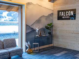 This stunning Méribel chalet boasts a stylish interior with a mountain-view window, a cozy seating area, and a modern console table.