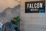 Falcon Méribel's lobby boasts a stylish design, featuring a sleek black sign against a rustic wood-paneled wall.