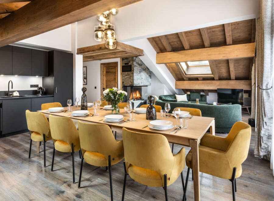 This stunning chalet boasts a spacious open-plan living area with a large dining table perfect for gatherings, a modern kitchen, and a cozy living room with a fireplace.
