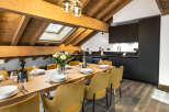 This stunning chalet boasts a spacious open-plan dining area with a large wooden table and mustard yellow velvet chairs, perfect for family gatherings.
