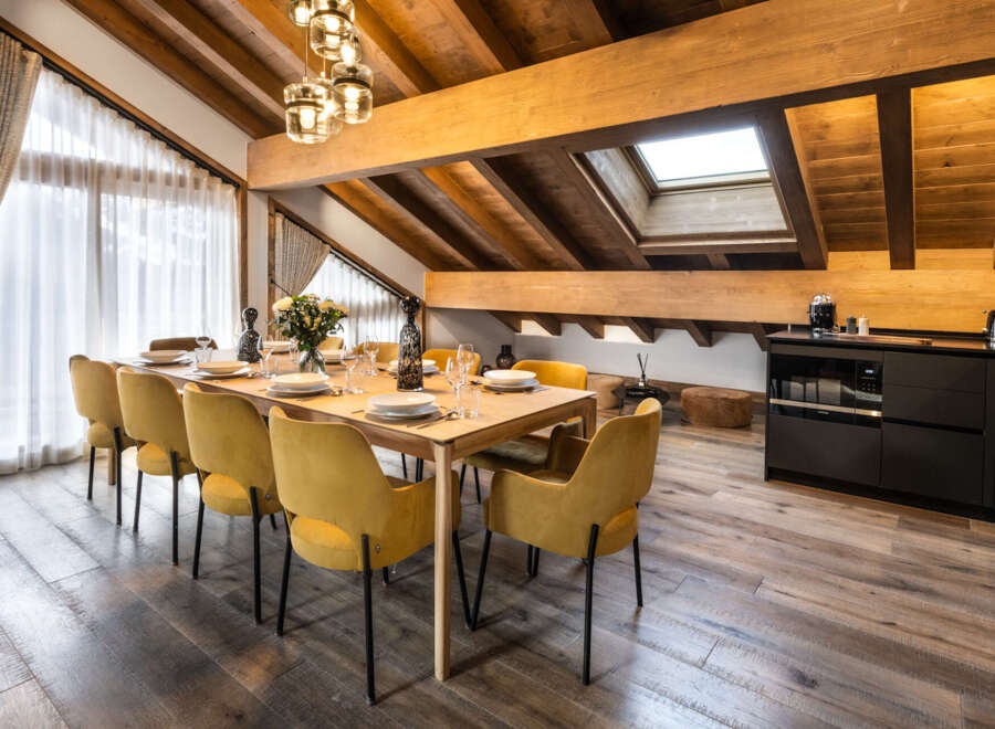 This stunning chalet boasts a spacious dining area with a large wooden table and plush mustard yellow chairs, perfect for family gatherings.