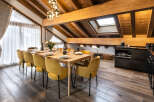 This stunning chalet boasts a spacious dining area with a large wooden table and plush mustard yellow chairs, perfect for family gatherings.