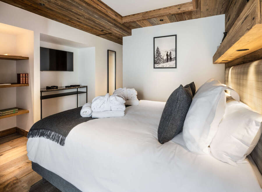 This luxurious bedroom boasts a cozy atmosphere with a wood-beamed ceiling and plush bedding.