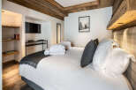 This luxurious bedroom boasts a cozy atmosphere with a wood-beamed ceiling and plush bedding.