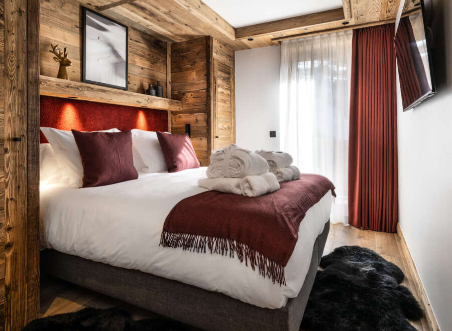 Cozy bedroom with a rustic wooden wall, plush bedding, and a warm color scheme.