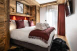 Cozy bedroom with a rustic wooden wall, plush bedding, and a warm color scheme.