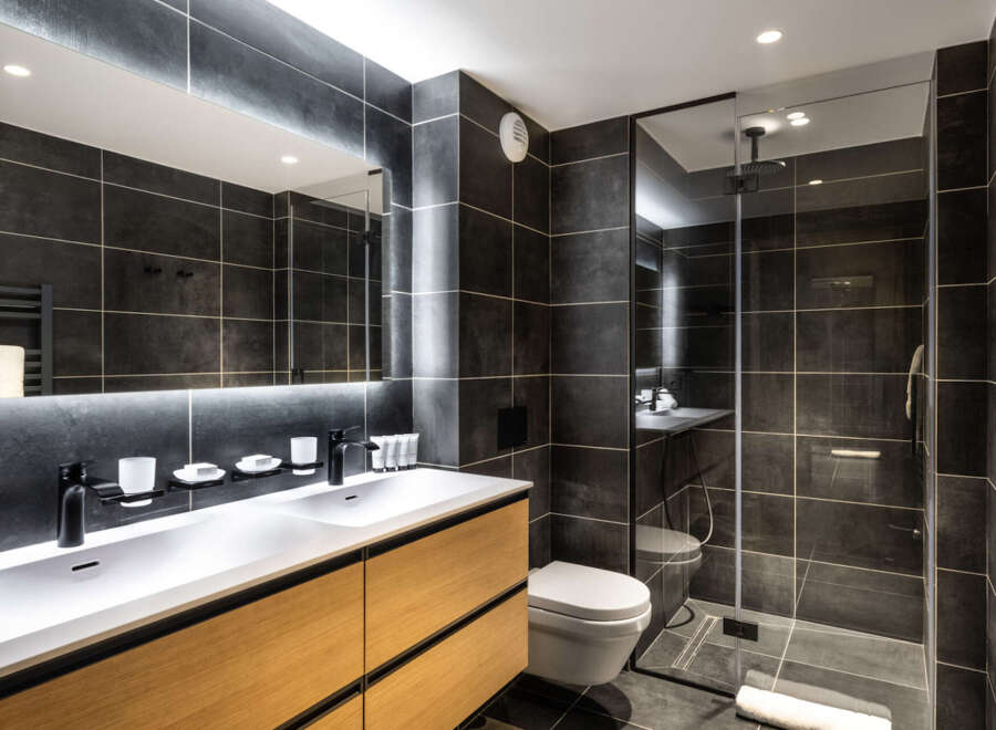 This modern bathroom boasts a double vanity with sleek black faucets and a spacious shower enclosure.