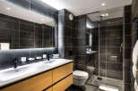 This modern bathroom boasts a double vanity with sleek black faucets and a spacious shower enclosure.