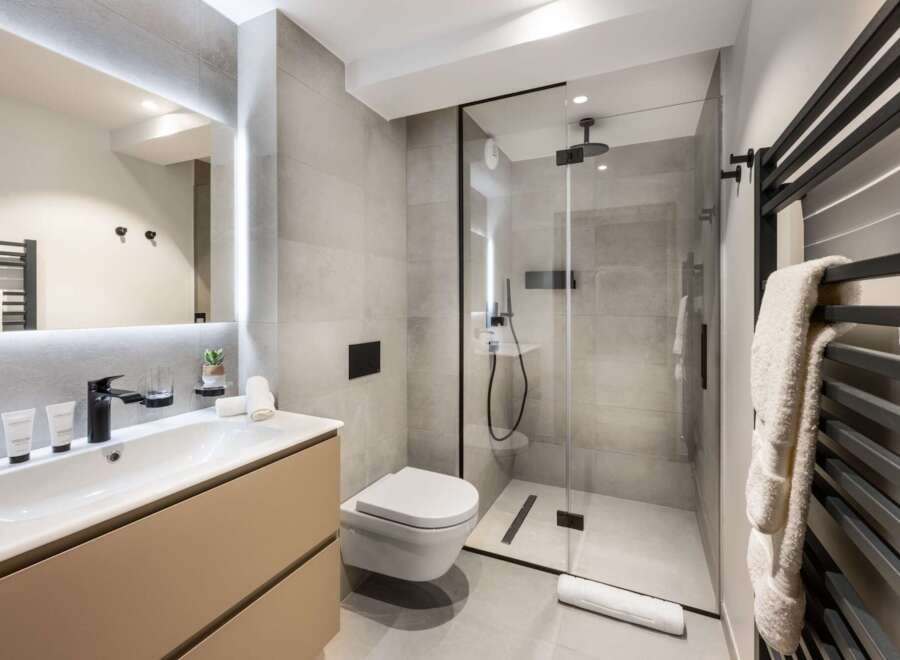 This modern bathroom boasts a sleek design with a walk-in shower, a floating toilet, and a stylish vanity.