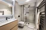 This modern bathroom boasts a sleek design with a walk-in shower, a floating toilet, and a stylish vanity.