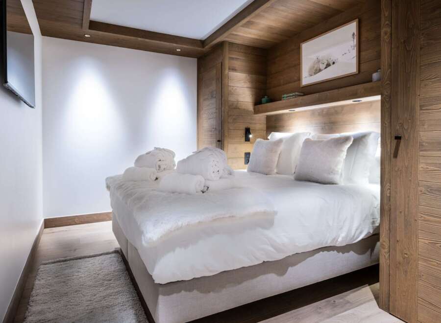 Experience luxury in this stunning bedroom featuring a cozy king-sized bed with plush bedding and fluffy pillows.