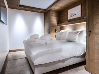 Experience luxury in this stunning bedroom featuring a cozy king-sized bed with plush bedding and fluffy pillows.