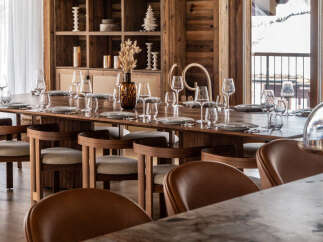 This stunning chalet boasts a spacious dining area with a long wooden table, surrounded by comfortable leather chairs.